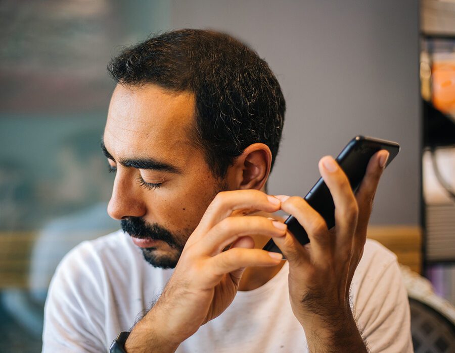 Blind man using the screen reader feature on a smart phone.