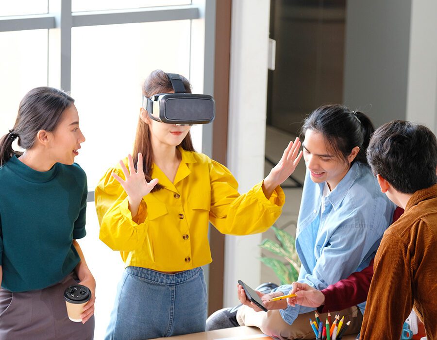 Team testing a VR headset with one person wearing the device and the others reviewing content on a tablet.