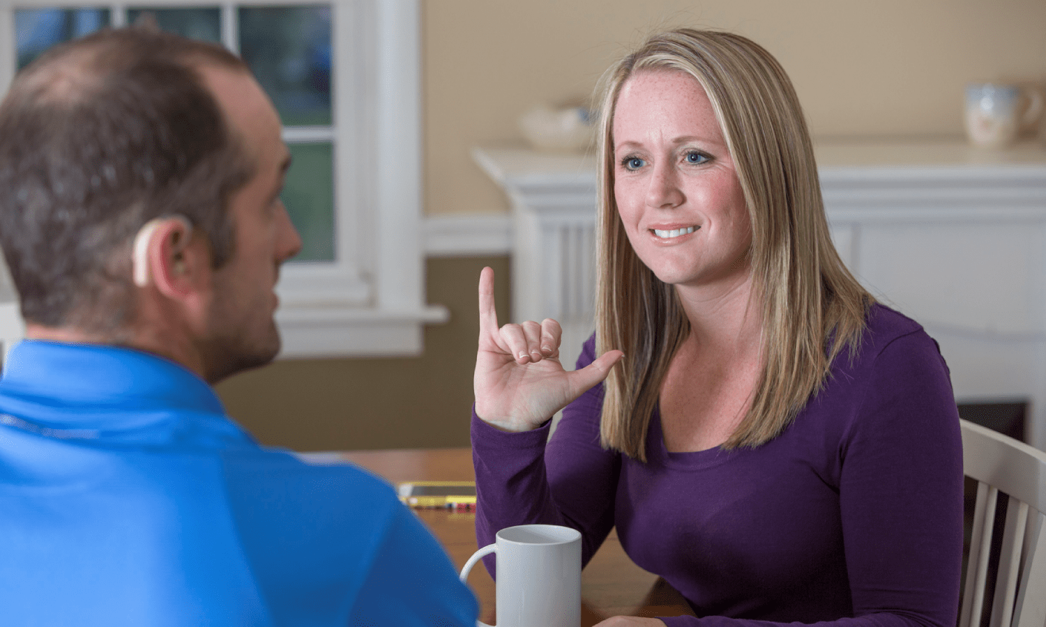 A woman and man sitting across from one another speaking with sign language.