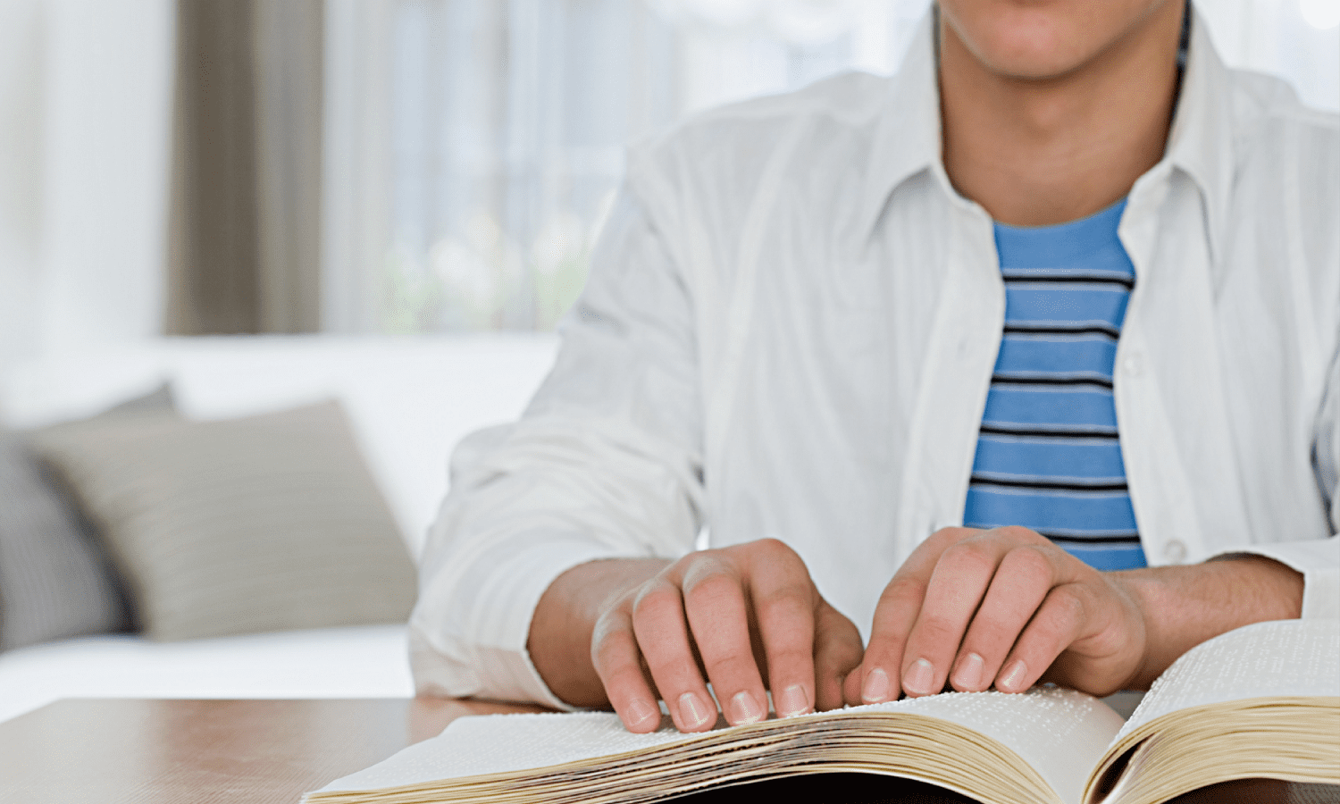 Close up view of hands reading over a book printed in braille.