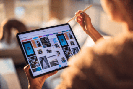 Over the shoulder view of a person using a stylus to interact with a tablet displaying a screen of images.