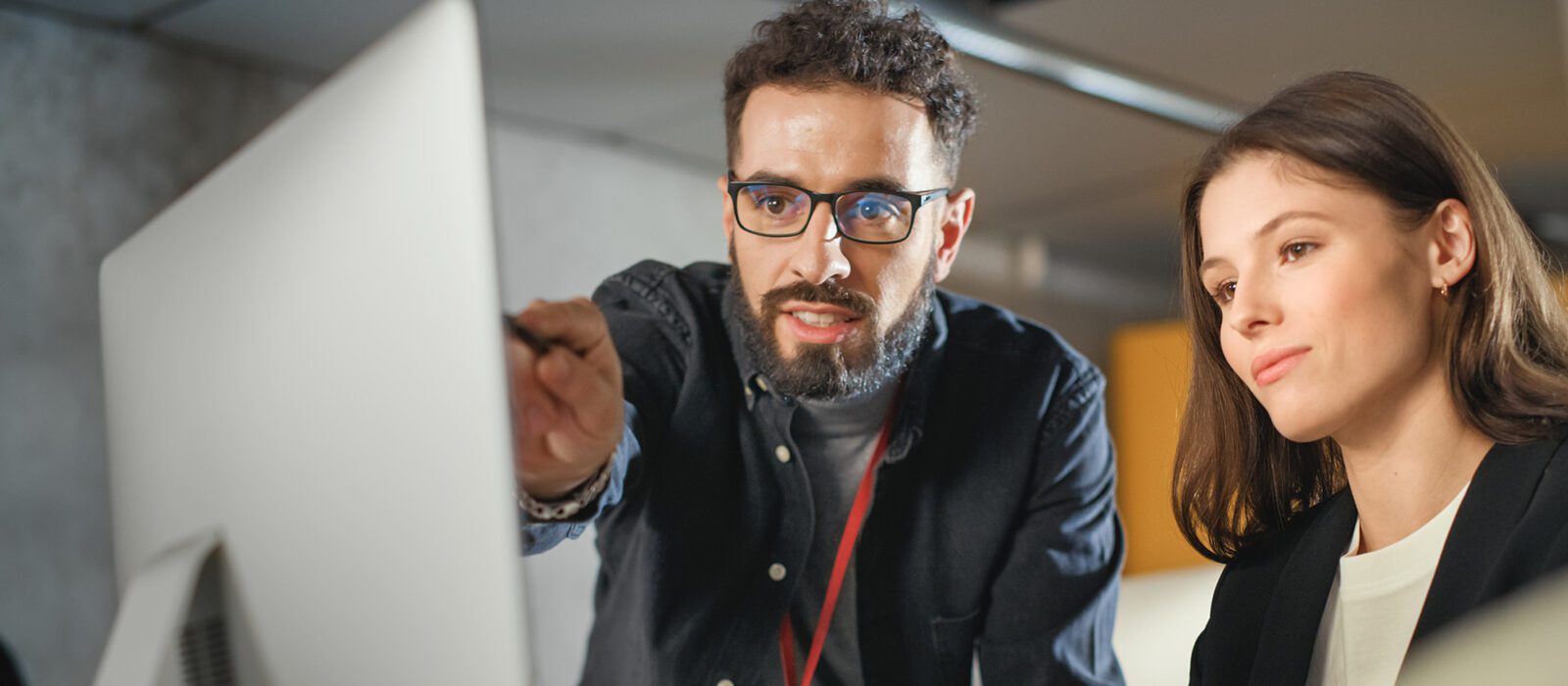 Colleague pointing to monitor in discussion with colleague