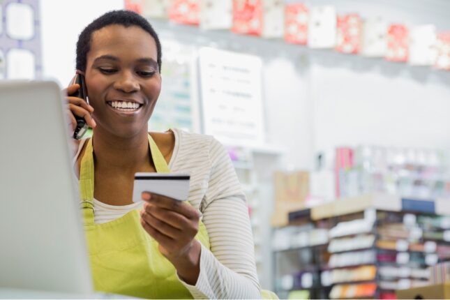 Person on a phone looking at a credit card.