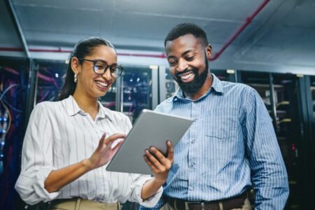 Two technicians using digital table while working in server room.