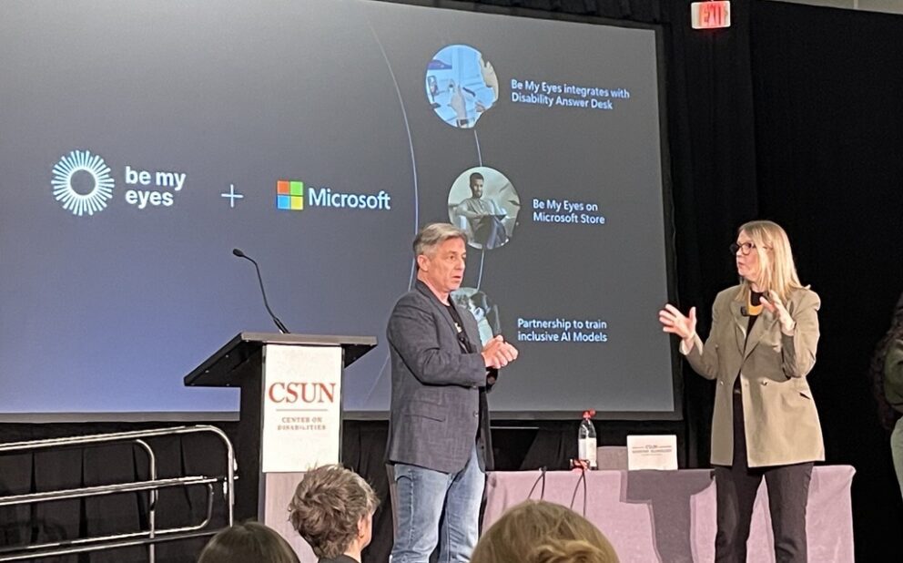 Jenny Lay-Flurrie of Microsoft and Mike Buckley, CEO of Be My Eyes onstage at CSUN 25. A large screen behind them holds their logos and presents milestones in the partnership.