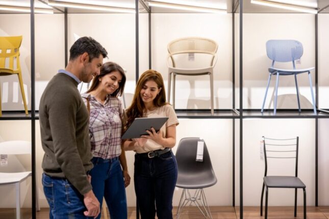 Retail salesperson uses an AI product recommendation chatbot to help a couple buy chairs for their house at a furniture store