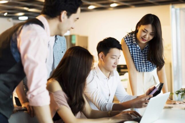 A group of workers gather together to discuss a topic.