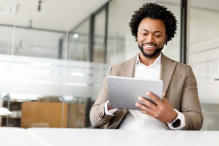 A Black businessman uses a tablet in the office to illustrate the benefits of smart conversational product discovery.