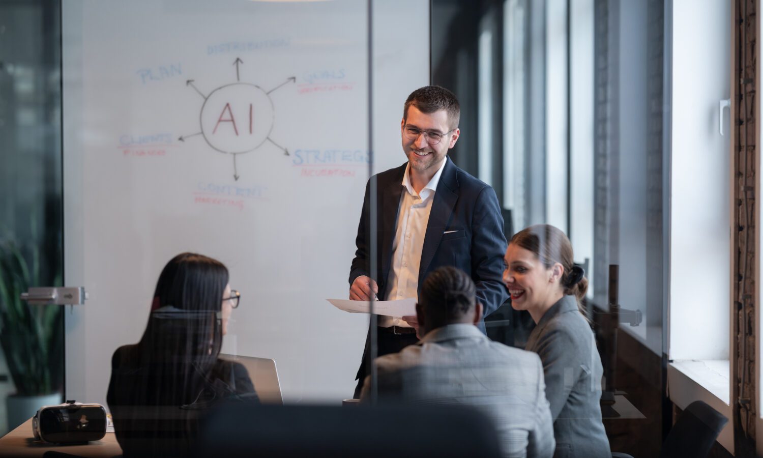 A business team in a meeting room discuss AI strategy, consulting, and implementation. There is a diagram on the whiteboard behind them.
